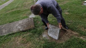 Dale McAllister, administrator of Union Baptist Church, tries to lift a headstone that had been broken off its base and put it back in place. Dozens of headstones have been vandalized in Union Baptist Cemetery.