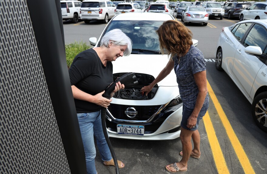 Sue Julien and Beth Hasebe try and connect Julien's Nissan Leaf to one of the newly installed electric car fast charging station at the Pittsford Wegmans. But the Leaf and Tesla vehicles are not able to connect to most standard public charging stations without an adapter.