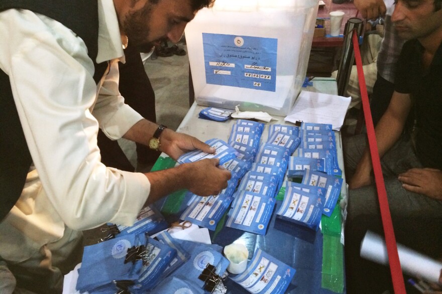 An Afghan election worker examines ballots to check for similar handwritten marks that would suggest ballot-stuffing fraud.