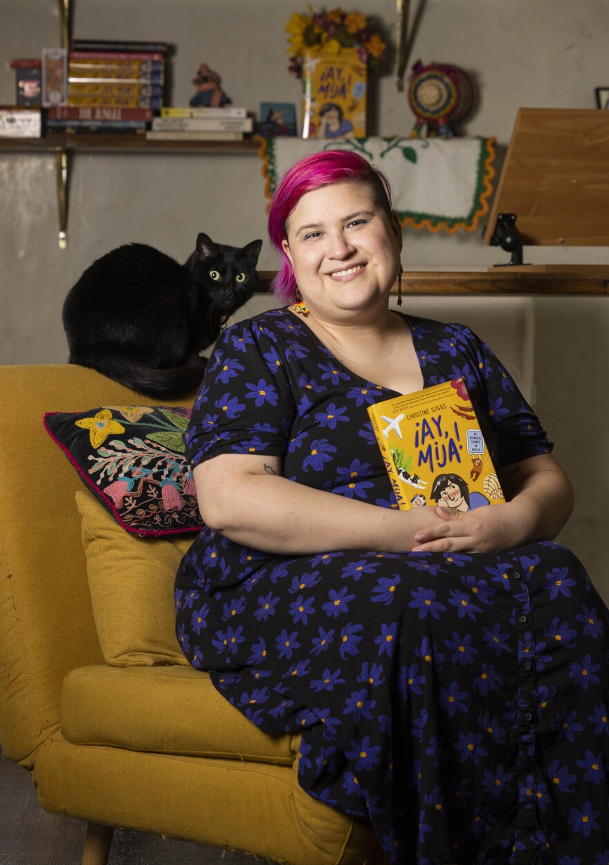 Christine Suggs released their first graphic novel, "Ay, Mija: My Bilingual Summer in Mexico." Suggs poses for a photo with cat Higgins at their home in Dallas on Wednesday, April 26, 2023.