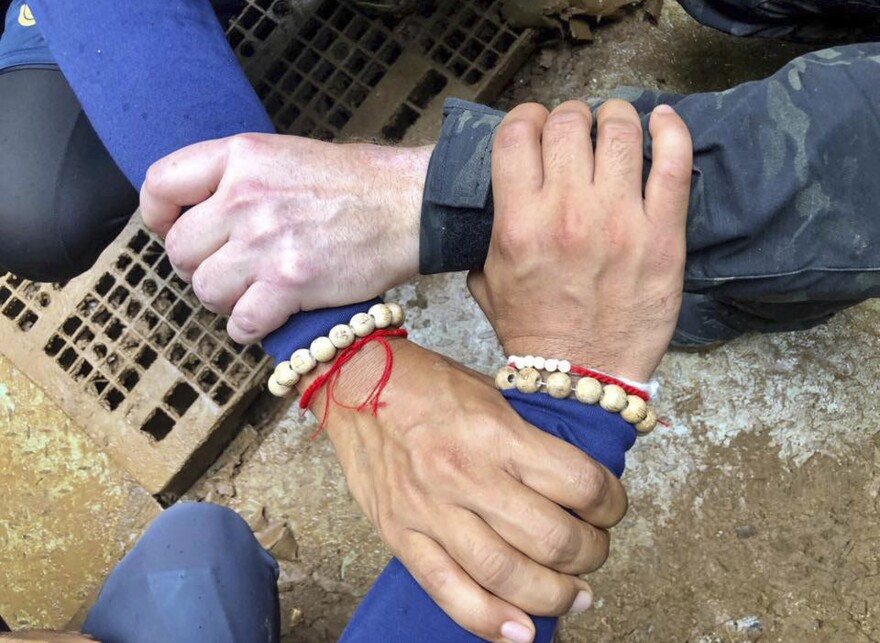 A photo released by the Thailand Navy SEAL Facebook page shows rescuers locking hands. Its caption says Thai and international rescuers are vowing to bring the boys home.