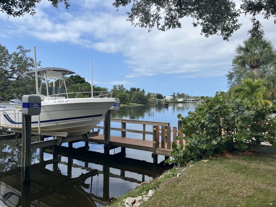 A boat on an elevated lift near a brown wood dock on Phillippi Creek
