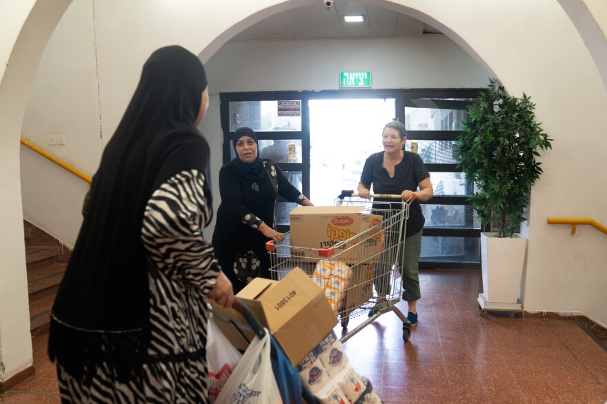 Smadar Tzimmerman (right) helps push a cart with donations into the community center in Lod, Israel.