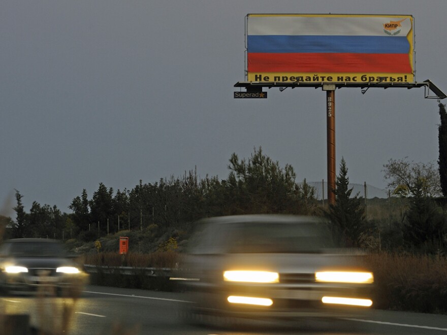A Cypriot business association has erected a billboard that reads, in Russian, "Do not betray us, brothers," over a Russian flag. Many Cypriots expect Russians will flee in the face of a eurozone deal.