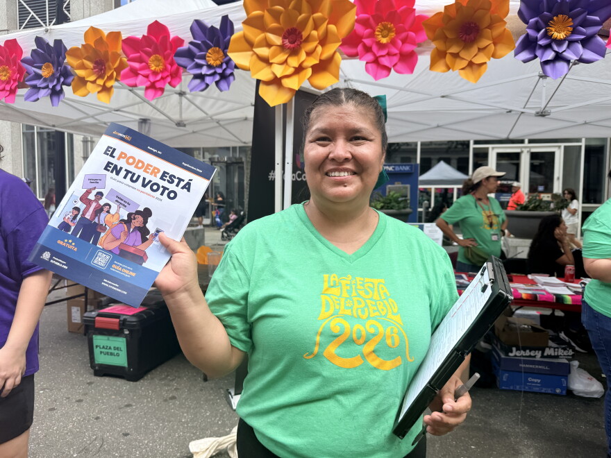 An El Pueblo volunteer holding a Spanish-language voter education guide at Fiesta del Pueblo, a festival El Pueblo organized in downtown Raleigh on Sept. 20, 2026.