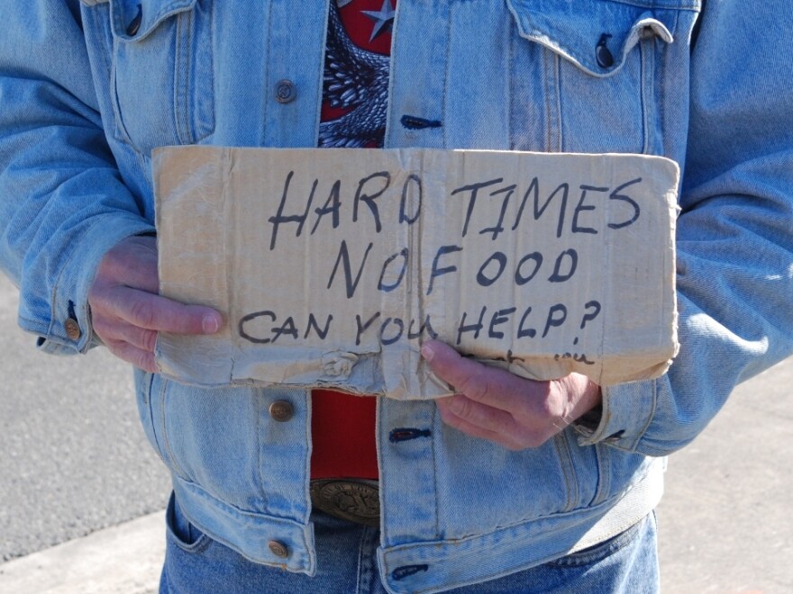 homeless person holding a sign