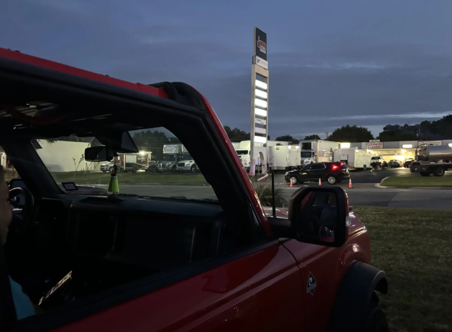 Wedgwood residents Leigh Ann and Mike Diaz sit inside their red Bronco as they watch film crews for the upcoming “Frisco King” take over a neighborhood strip mall on July 15, 2026.