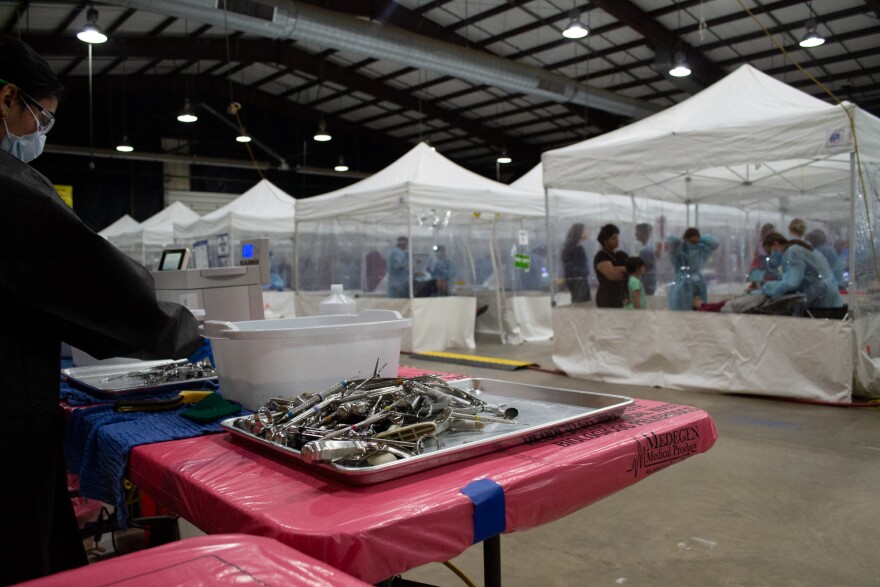 Volunteers sanitize medical equipment near the dental operatory area.