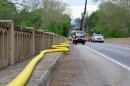 A yellow fire hose carries water to the west end of Elkton while a public works crew replaces the broken sections of water line under the bridge.