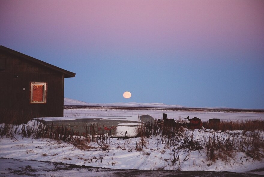 The moon sets behind a bluff