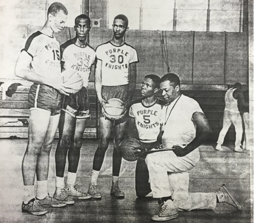 The Purple Knights pose on the court; Harold Sylvester is kneeling next to his coach.