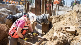 Archaeologist Victoria Swenson is screening grave shaft soil located under Vine Street in Evansville. During an underground infrastructure project in April, several graves were discovered likely dating from the 1800s. She's checking for nails or any 'mortuary goods' that might have been buried with the individual. Behind her is the work site for the underground utility work. This site wasn't open to the public, but it's an example of how archaeology can happen in unexpected places.
