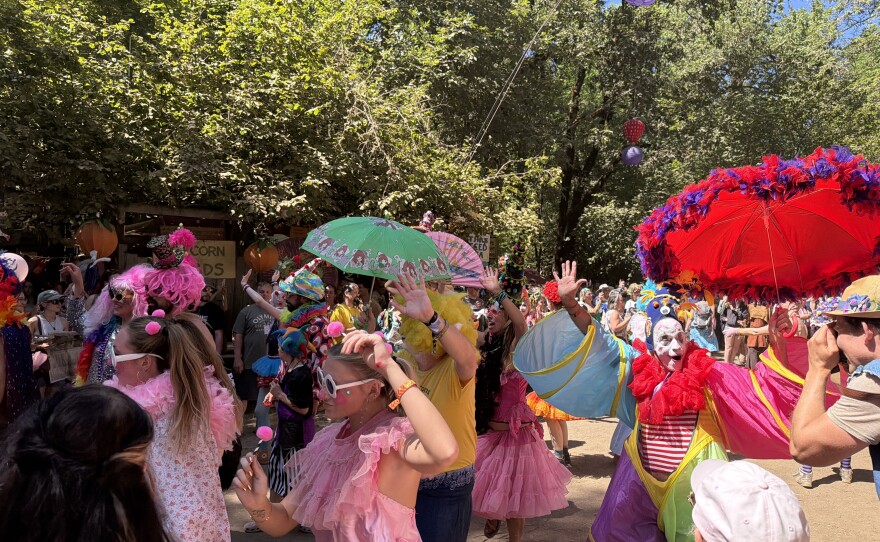 A parade featuring clowns walks through the 2026 Oregon Country Fair.