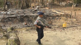 A Myanmar security officer walks past burned Rohingya houses in Ka Nyin Tan village of suburb Maungdaw, northern Rakhine state of western Myanmar on Sept. 6, 2017. 