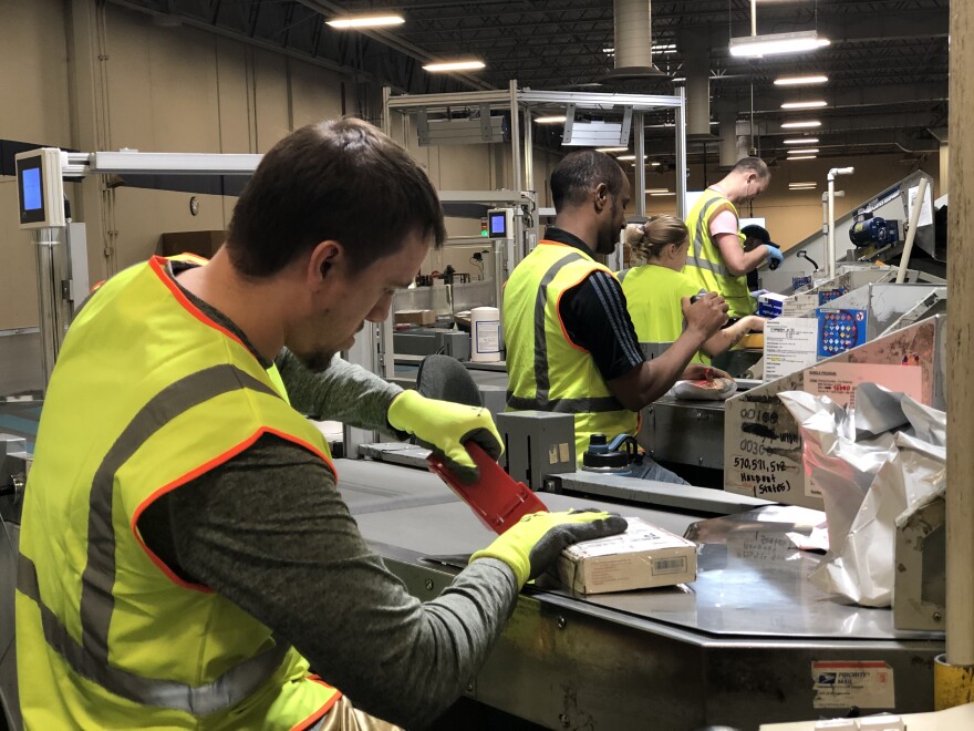 Workers in safety gear look at packages.
