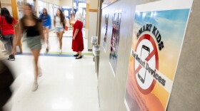 Students walk past a sign that reads Smart Kids Not Smart Devices.