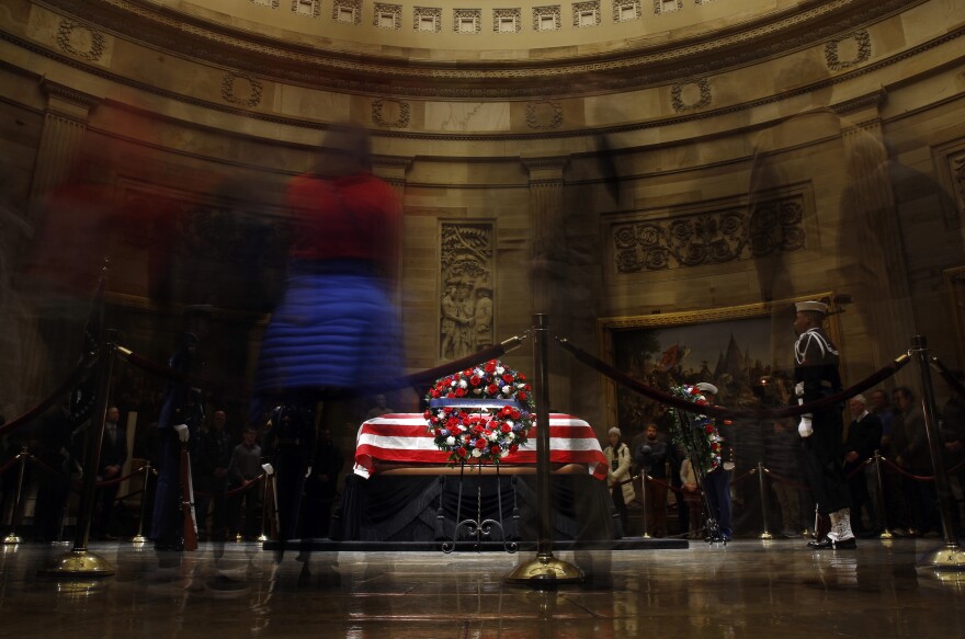 Visitors file past the flag-draped casket of former President George H.W. Bush as he lies in state in the Capitol Rotunda in Washington, Monday, Dec. 3, 2018. 