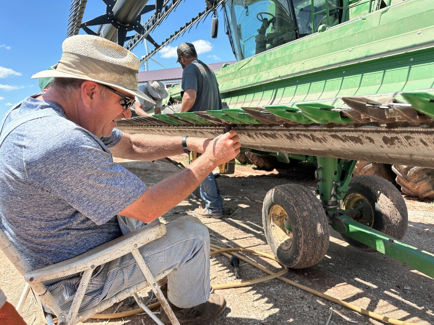 Kevin Brewer sits in a folding chair to work on his combine. He said they are getting machines ready to pick up canola.