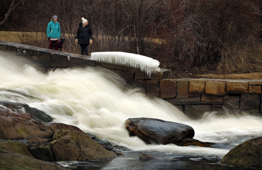 Emily Pratt and her mother, Sharon Pratt, of Rockport, Maine, pause to watch the rushing waters of the Megunticook River Falls where it flows into Camden Harbor, Friday, Feb. 23, 2018, in Camden, Maine. The unseasonably warm weather earlier in the week created a lot of snowmelt that has raised the level of the state's rivers.