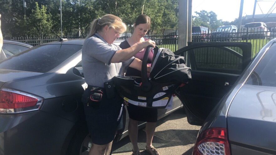 Pictured holding a car seat. 