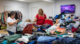 Two women search through tables filled with clothes.