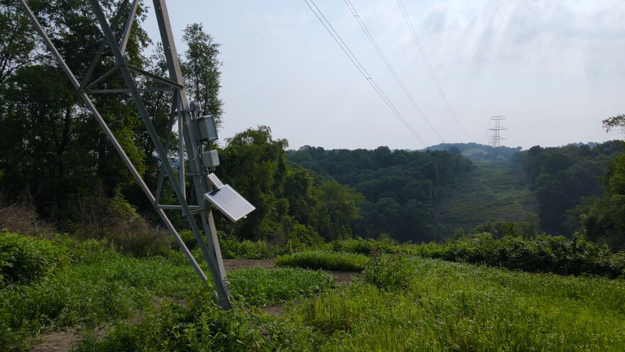 A panel and other equipment are attached to a support of a transmission line.