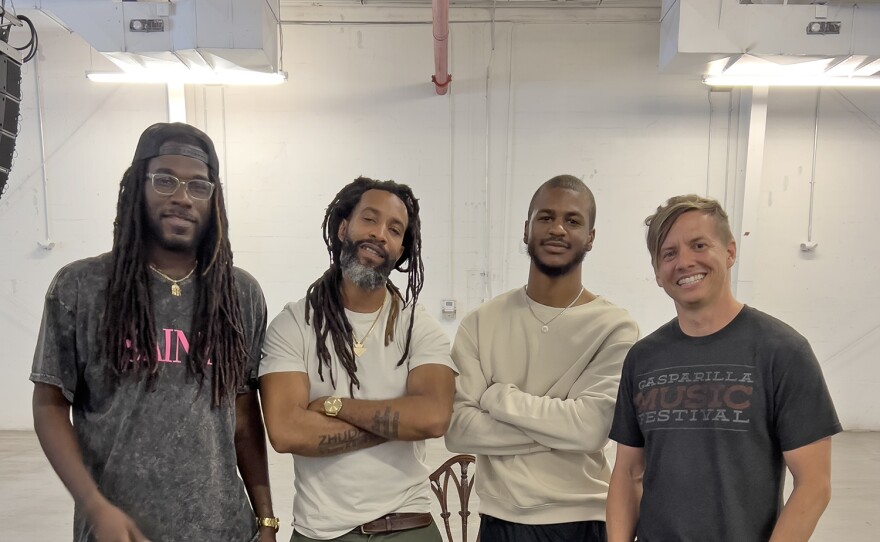 Four men stand pose in a row on set. They are some of the film's director and crew. 