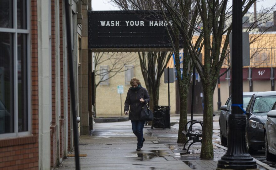 A woman walks past a closed cinema in Norwood, Massachusetts,  where the marquee reads, "Wash your hands." 