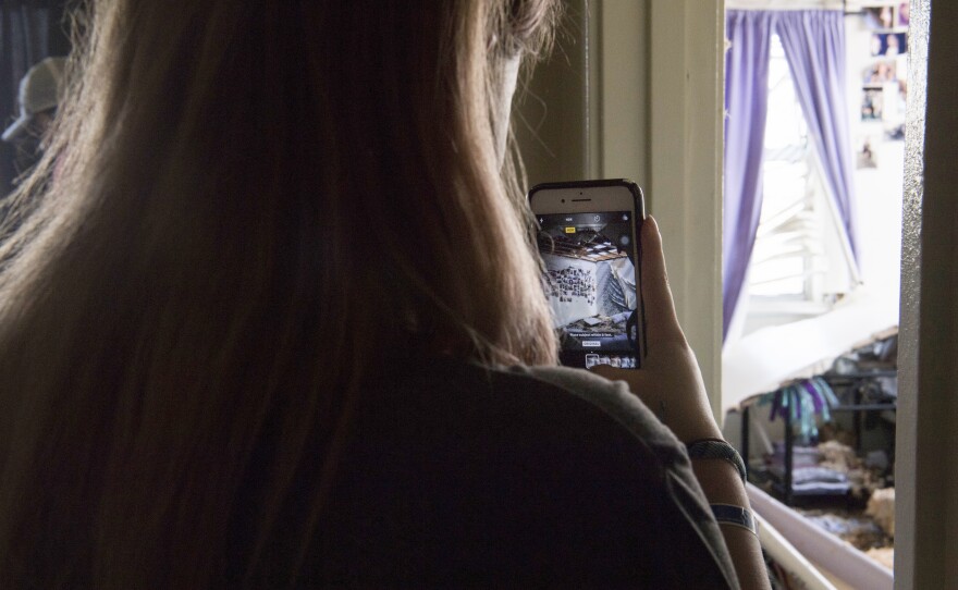 Zoe Reeves photographs the damage done to her bedroom by Hurricane Michael at Tyndall Air Force Base.