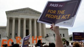 People hold placards at a rally in front of the US Supreme Court to call on the Senate to pass the For the People Act in Washington DC.
