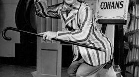 A black-and-white photo of actor Mickey Rooney posing with a cap and a cane, mid-dance.