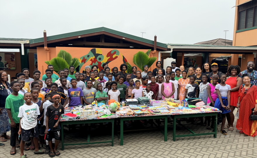 A large group of people surround a table in an African village.