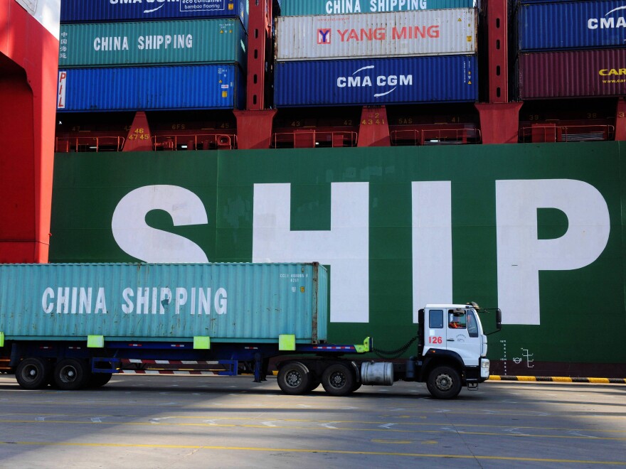 A truck carries a container past a ship at the port in Qingdao, in China's Shandong province on Feb. 15, 2016. China's sagging economy has hurt the shipping industry this year.