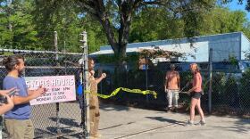 Co-founder Sarah Goff cuts a repurposed caution tape ribbon to celebrate the grand opening of Renovator Reuse on Friday, May 3, 2024. (Kristin Moorehead/WUFT News)