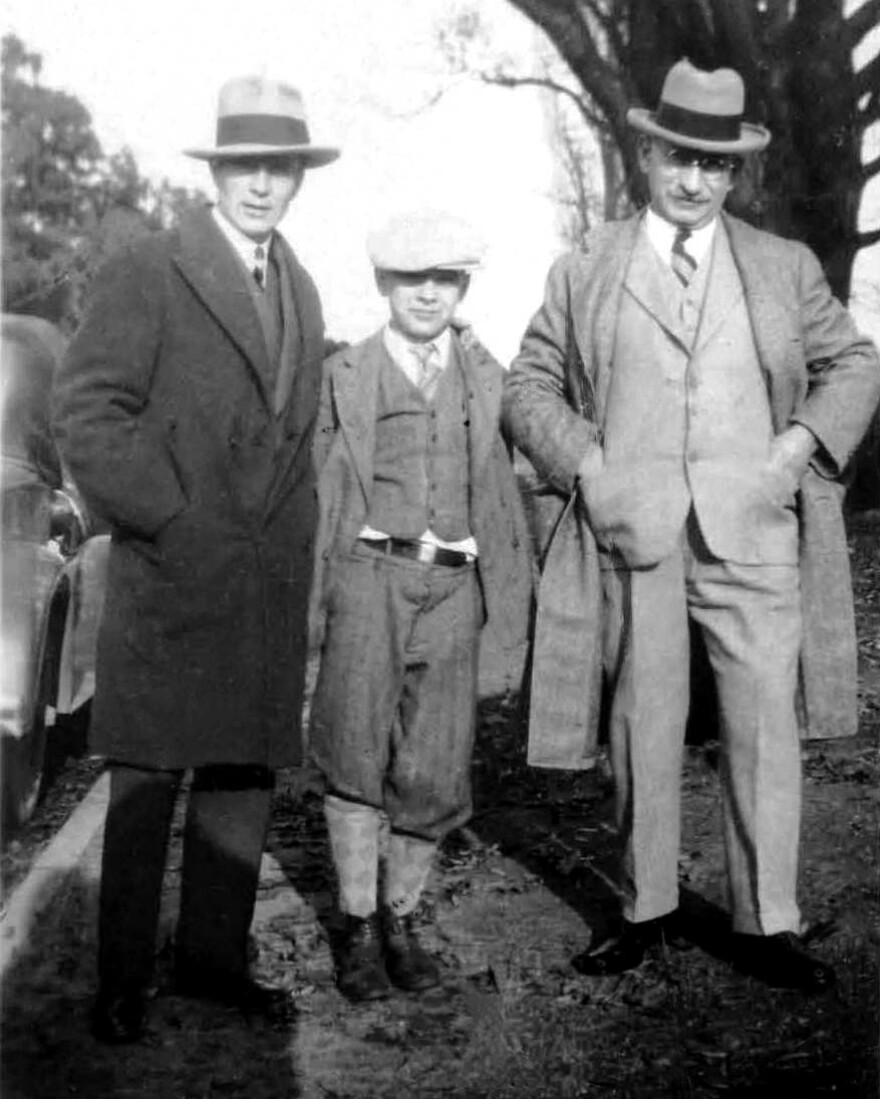 Historic photo of two adult men posing with a young boy