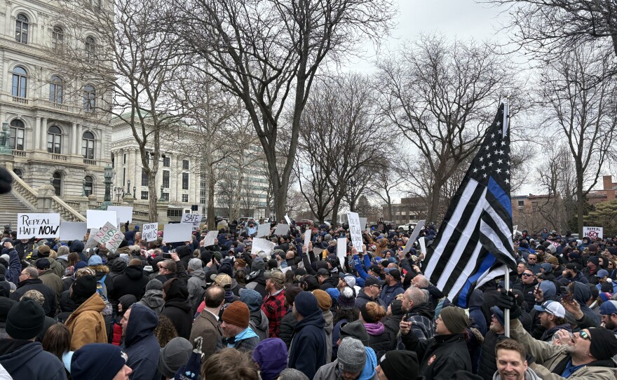 A large group of protesters holding signs and a flag