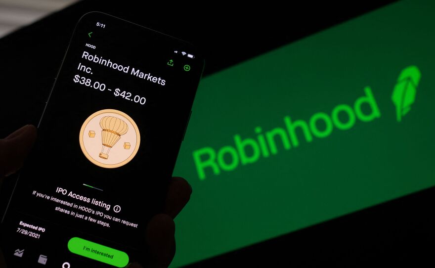 A phone screen shows Robinhood's IPO listing, with the words "Robinhood Markets Inc. $38.00-$42.00." Behind it is a screen with a dark green background and the company's name and feather logo in light green.