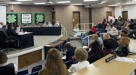 Peoria School Board 150 meeting March 23. The public looks across a horseshoe divider as committee members on a stage across the room deliberate.