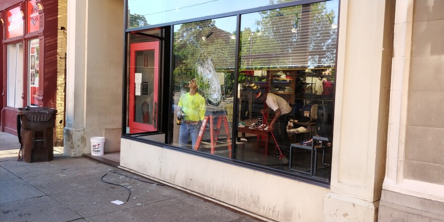 A man works to repair a broken storefront window on Vine Street Saturday morning.
