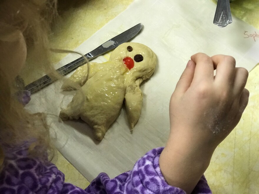 A little girl decorates her grittibanz.
