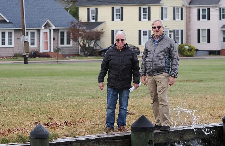 Two individuals stand near a dock