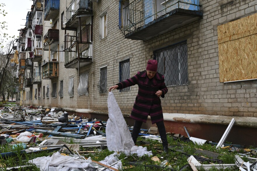 <strong>April 14:</strong> A woman looks for goods dropped from the apartment building partly damaged by shelling, in Kramatorsk, Ukraine.