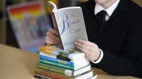 An educator poses with books, including "The Bluest Eye," by Toni Morrison, that have been the subject of complaints from parents in Salt Lake City, Utah. The wave of book bannings around the country has reached a level not seen for decades. (Rick Bowmer/AP)