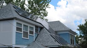 A blue house with solar panels on the roof at a sloped angle.