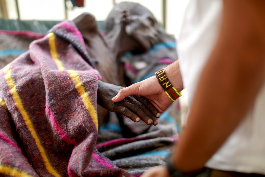 The kids in the camp made a beaded bracelet for Dr. Nav, who clasps the hand of a patient in the tuberculosis ward.