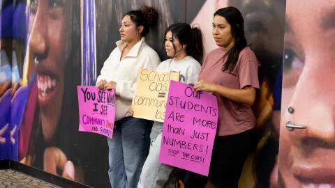Tulsa community members hold protest signs at the back of the Tulsa Public Schools Board of Education meeting Monday night.