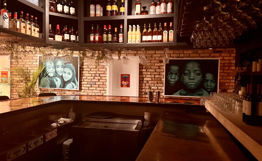 The walls upstairs at Off The Clock, from the stairs to the entrance, are sprawled with work by the restaurant’s resident artist, Haiti-born Rousell Dad.