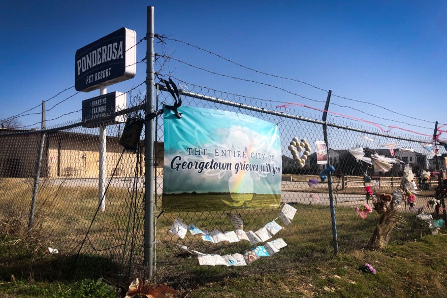 A memorial decorated with a banner, flowers and pictures of dogs outside of the closed Ponderosa Pet Resort in Georgetown