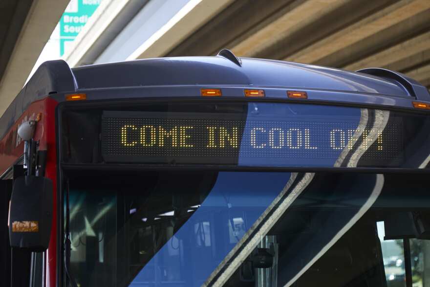 A sign on a bus reads "Come in, cool off!"
