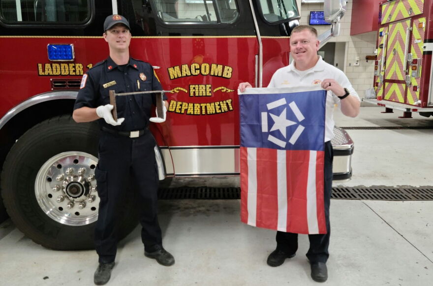 Lt. Ethan Taylor (left) holds the remnant from the World Trade Center, while Chief Dan Meyer displays the Freedom Flag.